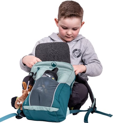 Ein Junge verstaut eine Schaumstoffmatte in einem Rucksack mit einer Trinkflasche.