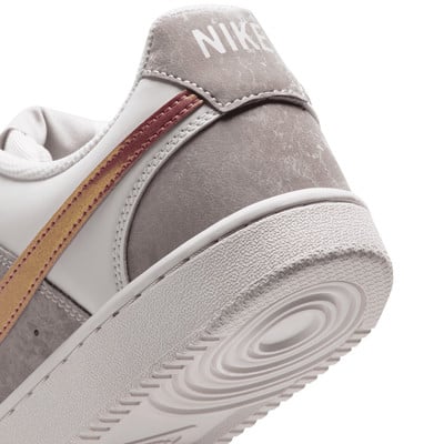 Egy fehér Nike cipő hátuljának részlete szürke és arany elemekkel. Egy fehér Nike cipő hátuljának részlete szürke és arany elemekkel.