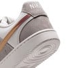 Egy fehér Nike cipő hátuljának részlete szürke és arany elemekkel.