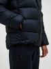 Ein Mann legt seine Hand in die Tasche einer dunklen Daunenjacke.
