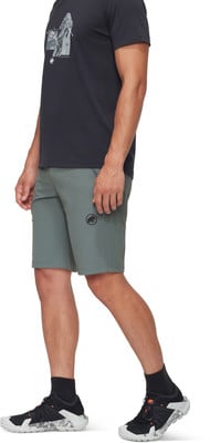Ein Mann in grauer Hose und schwarzem T-Shirt mit Bergmotiv.