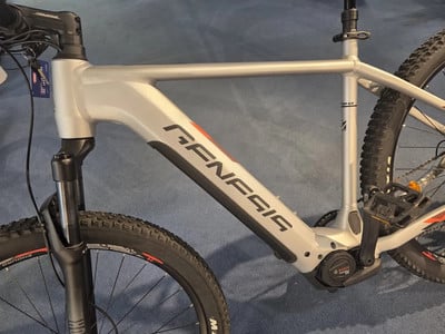 Silbernes Genesis E-Bike mit schwarzen Details und Logo auf dem Rahmen. Silbernes Genesis E-Bike mit schwarzen Details und Logo auf dem Rahmen.