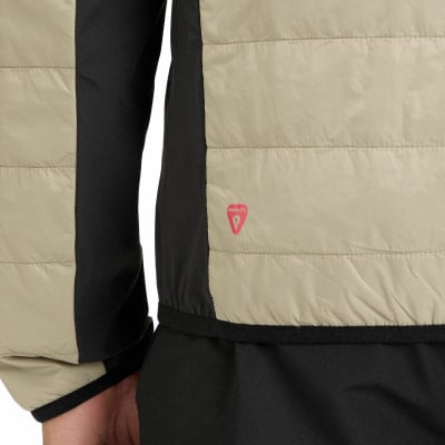 Detail einer Jacke mit Primaloft-Logo in Beige und Schwarz. Detail einer Jacke mit Primaloft-Logo in Beige und Schwarz.