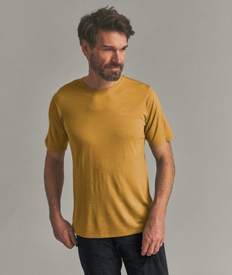 Mann in einem senffarbenen T-Shirt mit kurzen Ärmeln und schwarzer Hose. Mann in einem senffarbenen T-Shirt mit kurzen Ärmeln und schwarzer Hose.