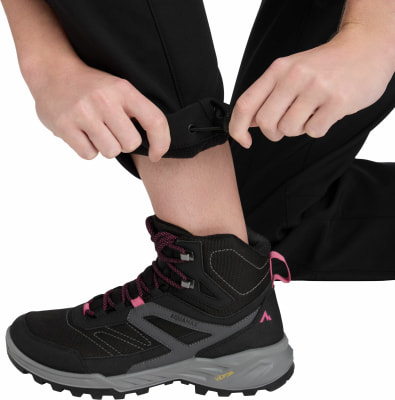 Füße in Wanderschuhen und schwarzer Hose mit verstellbarem Saum.