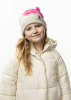 Ein junges Mädchen mit blonden Haaren und einem Lächeln trägt eine Winterjacke und eine Mütze.