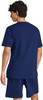 Ein Mann in einem dunkelblauen T-Shirt und Shorts von hinten gesehen.