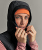 Eine Frau mit orangefarbener Mütze und schwarzer Jacke richtet ihre Kapuze.