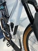 Detail eines weißen Mountainbikes mit Dämpfer und braunen Reifen.