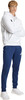 Junger Mann im weißen Hoodie und dunkelblauer Jogginghose.