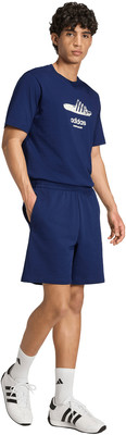 Ein Mann in einem dunkelblauen Adidas-T-Shirt und Shorts mit weißen Turnschuhen. Ein Mann in einem dunkelblauen Adidas-T-Shirt und Shorts mit weißen Turnschuhen.
