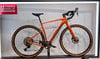 Ein orangefarbenes Cannondale Gravelbike mit schwarzem Lenker und braunen Felgen.