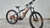 Ein graues KTM E-Bike mit orangefarbenen Akzenten steht auf Beton.