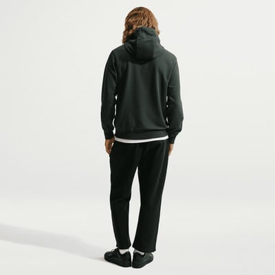 Ein Mann von hinten in einem dunkelgrünen Hoodie und schwarzer Jogginghose. Ein Mann von hinten in einem dunkelgrünen Hoodie und schwarzer Jogginghose.