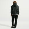 Ein Mann von hinten in einem dunkelgrünen Hoodie und schwarzer Jogginghose.