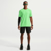 Ein Mann in einem grünen Hemd und schwarzen Shorts mit Nike-Logo.