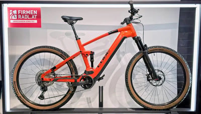 Ein orangefarbenes Cube Mountainbike mit schwarzen Details auf einem Ständer. Ein orangefarbenes Cube Mountainbike mit schwarzen Details auf einem Ständer.