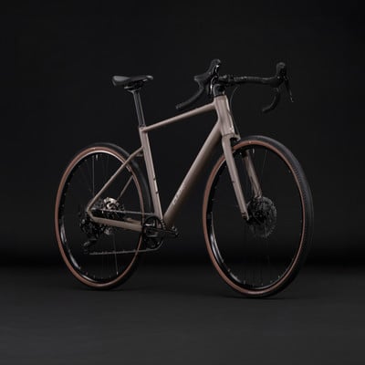 Graues Gravelbike mit braunen Reifen auf schwarzem Hintergrund. Graues Gravelbike mit braunen Reifen auf schwarzem Hintergrund.