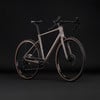 Graues Gravelbike mit braunen Reifen auf schwarzem Hintergrund.