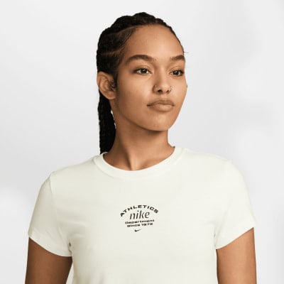 Eine Frau in einem weißen T-Shirt mit Nike-Logo und dem Aufdruck Athletics. Eine Frau in einem weißen T-Shirt mit Nike-Logo und dem Aufdruck Athletics.