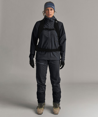 Frau in Skikleidung mit Rucksack und Mütze auf grauem Hintergrund. Frau in Skikleidung mit Rucksack und Mütze auf grauem Hintergrund.