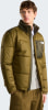 Ein Mann in einer olivgrünen Daunenjacke mit dunkleren Schultern und Brusttasche.