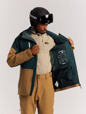 Ein Mann in einer Skijacke und einem Helm untersucht die Innentaschen der Jacke. Ein Mann in einer Skijacke und einem Helm untersucht die Innentaschen der Jacke.