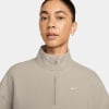 Frau in einem beigen Pullover mit kurzem Reißverschluss und Nike-Logo.