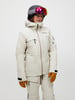 Skifahrerin in weißer Jacke und Hose, mit Helm und Brille.