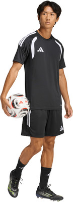 Ein junger Mann im schwarzen Fußballtrikot und Shorts hält einen Ball. Ein junger Mann im schwarzen Fußballtrikot und Shorts hält einen Ball.