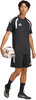 Ein junger Mann im schwarzen Fußballtrikot und Shorts hält einen Ball.
