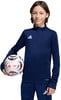 Ein Junge in dunkelblauer Sportkleidung hält einen Fußball.