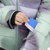 Eine Hand steckt eine blaue Karte mit dem Intersport-Logo in eine Jackentasche.