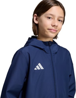 Junge in dunkelblauer Adidas-Jacke lächelt in die Kamera. Junge in dunkelblauer Adidas-Jacke lächelt in die Kamera.