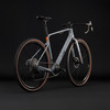 Graues Gravelbike mit orangefarbenen Details und braunen Reifen.