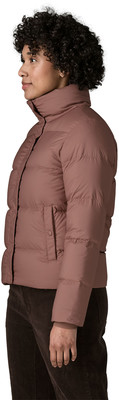 Eine Frau in einer rosa Daunenjacke und braunen Hose von der Seite. Eine Frau in einer rosa Daunenjacke und braunen Hose von der Seite.