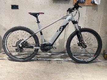 Graues Mountainbike mit schwarzen Rädern und rotem Sattel.
