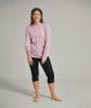 Eine Frau in einem rosa Langarmshirt und schwarzen 3/4-Hosen.
