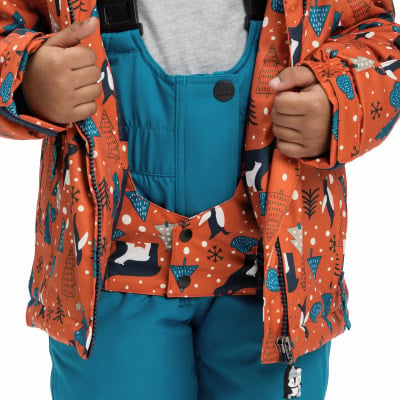 Kind in oranger Winterjacke mit Pinguinen und blauer Latzhose. Kind in oranger Winterjacke mit Pinguinen und blauer Latzhose.