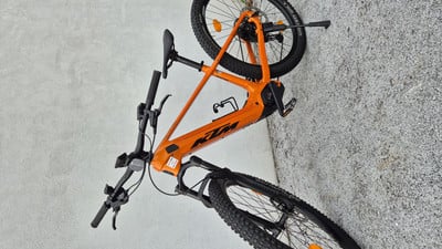 Ein orangefarbenes KTM E-Bike auf einer grauen, kiesartigen Oberfläche.