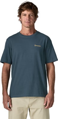 Ein Mann in einem dunkelblauen T-Shirt mit Logo und einer beigen Hose steht. Ein Mann in einem dunkelblauen T-Shirt mit Logo und einer beigen Hose steht.