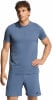Ein Mann in einem blauen Adidas-T-Shirt und Shorts vor weißem Hintergrund.