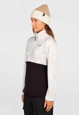 Mädchen in einer beige-weißen Mütze und einer Jacke mit Aufdruck und schwarzem Unterteil.