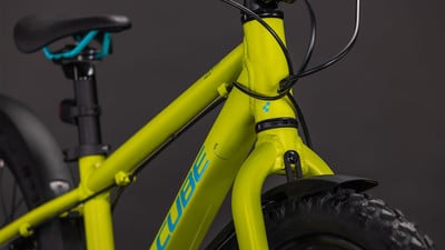 Ein grünes Cube Kinderfahrrad mit blauen Akzenten und schwarzem Sattel. Ein grünes Cube Kinderfahrrad mit blauen Akzenten und schwarzem Sattel.