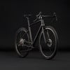 Ein schwarzes Gravelbike mit Scheibenbremsen und breiten Reifen vor schwarzem Hintergrund.