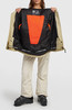 Damen-Skijacke in Beige mit orangefarbenem Fleecefutter und schwarzen Skischuhen.