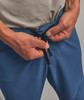 Ein Mann zieht die Kordel seiner blauen Hose enger.