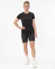 Eine Frau in einem dunklen T-Shirt und Shorts steht vor einem weißen Hintergrund.
