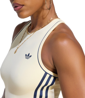 Eine Frau in einem cremefarbenen Oberteil mit dunkelblauen Streifen und Adidas-Logo. Eine Frau in einem cremefarbenen Oberteil mit dunkelblauen Streifen und Adidas-Logo.