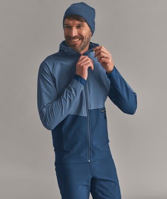 Ein Mann in einer blauen Jacke und Mütze schließt den Reißverschluss. Ein Mann in einer blauen Jacke und Mütze schließt den Reißverschluss.